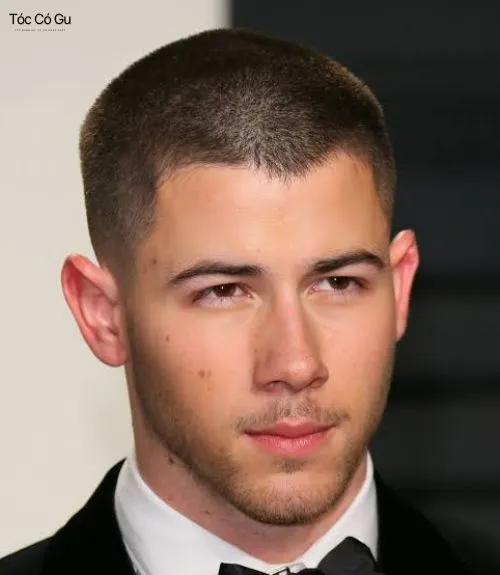 Người đàn ông có kiểu tóc Burr buzz cut với đường kẻ vạch bên hông. Anh có râu ngắn và mặc áo thun polo