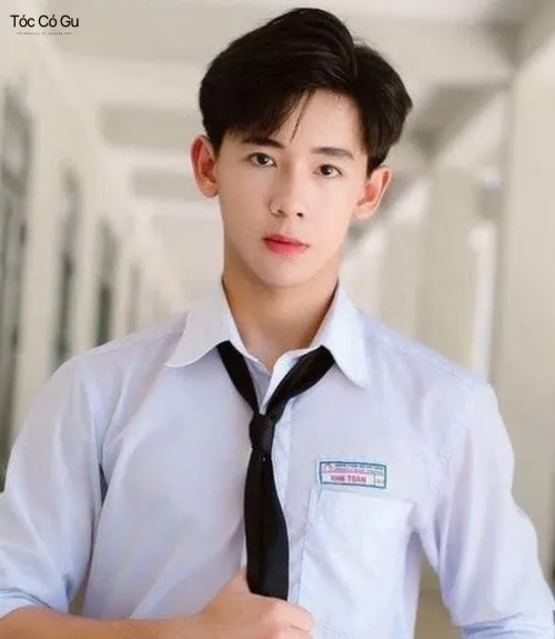Tóc Side Part là gì? Top 10 kiểu tóc Side Part quốc dân hiện nay Nam sinh để tóc Side Part rủ tự nhiên, mặc áo sơ mi trắng và cà vạt trong hành lang.