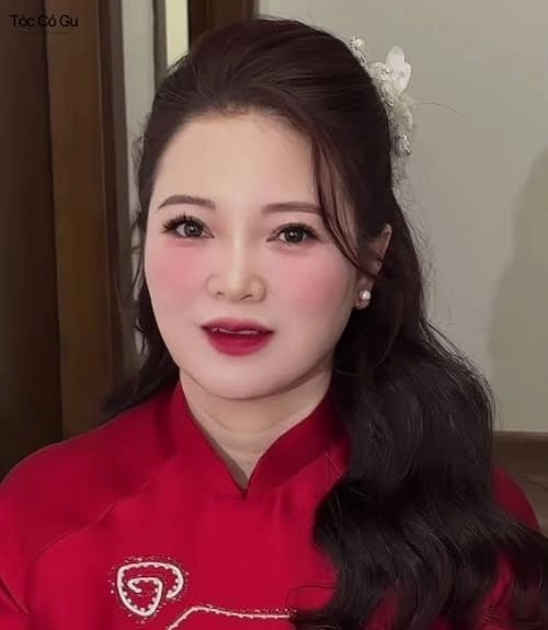 15+ kiểu tóc đẹp cho mẹ cô dâu và chú rể trẻ trung, sang trọng Tóc búi xoăn thấp tạo cảm giác mềm mại và tự nhiên cho tổng thể.